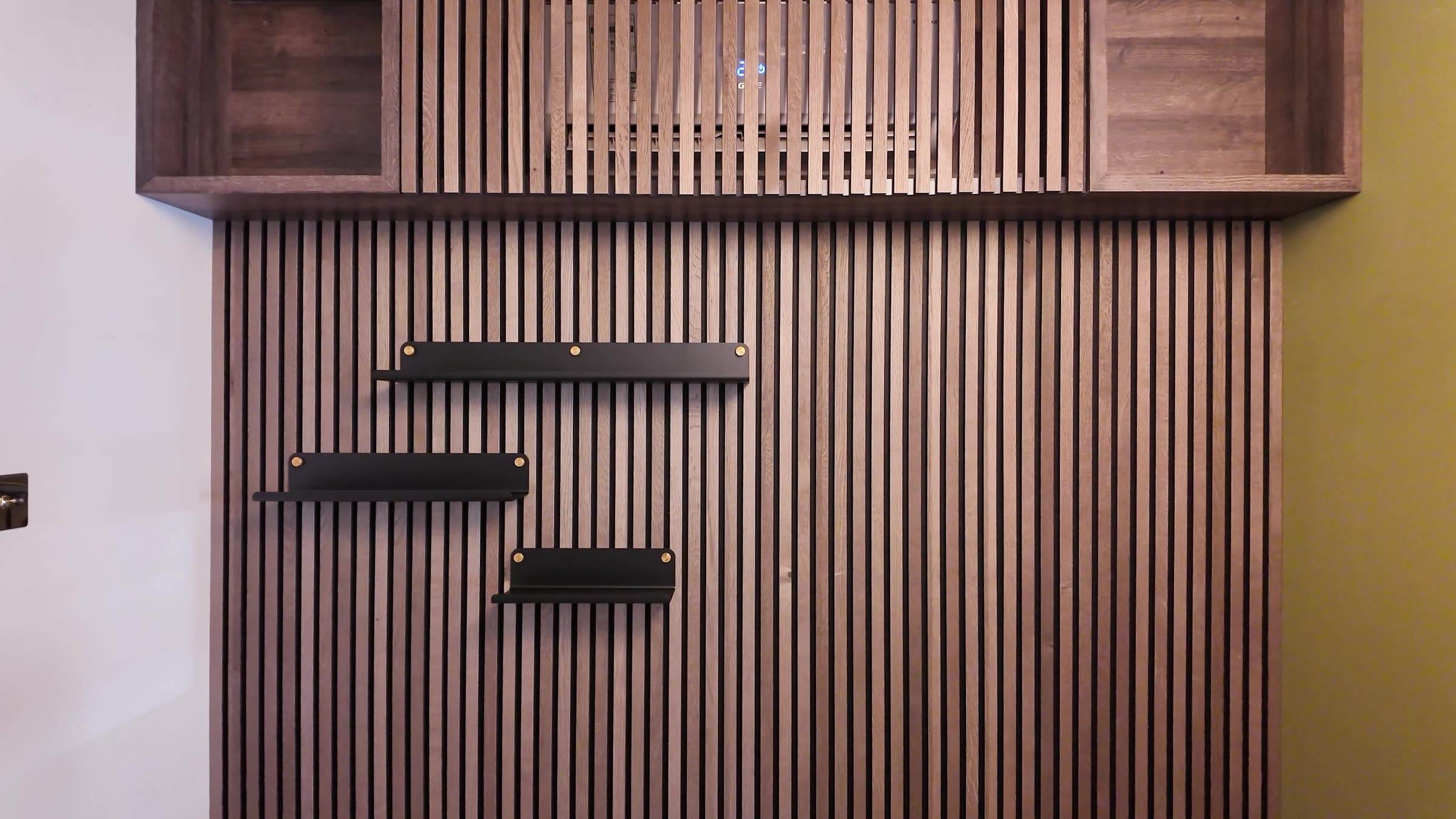 Akupanel slat grille concealing an air conditioner above a slatted wall with black shelves